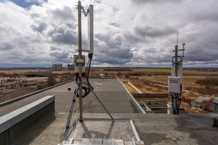 Panel antenna of GSM DCS UMTS LTE bands, GPS antenna and outdoor remote radio unit are as part of communication equipment of basic station are installed on the tubular mast on the roofの写真素材