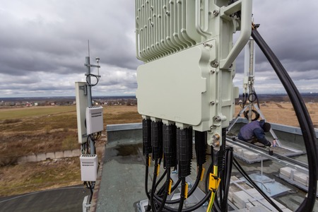 Panel antenna of GSM DCS UMTS LTE bands and outdoor remote radio unit are as part of communication equipment of basic station are installed on the tubular mast on the roofの写真素材