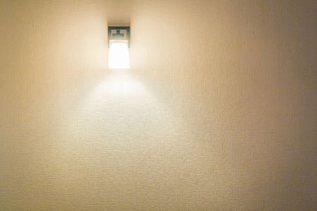 A glowing modern aluminum led lamp on the texture  wall of apartment after construction. Free space for textの写真素材