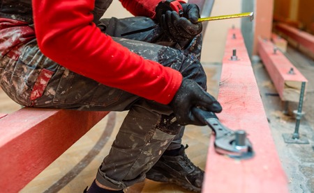 Construction worker screws bolts up tight  on the stud on the wooden block in apartment that is under construction, remodeling, renovation, overhaul, extension, restoration and reconstruction. Concept of total home improvementの写真素材