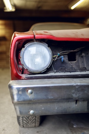 Restoration of classic car. Close up view front side classic car, front headlight of a broken dusty car during road accident and has been reconstructed in garage. Restoration of classic car.の写真素材