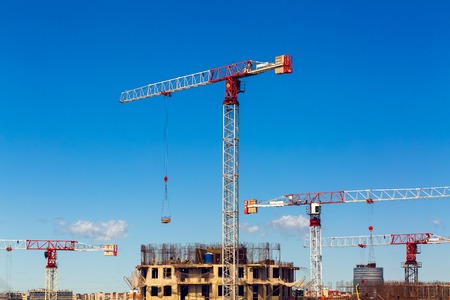Large construction site including several cranes working on a building complex, workers,...