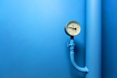 Manometer of center plumbing system with indicator of pressure  on the big diameter water pipe of plumbing system and the blue wall is a background. Spase for your text.の写真素材
