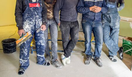Workers and builders and foreman are as gang with dirty uniform are staying in apartment that is under construction, remodeling,renovation,extension, restoration, overhaul and reconstructionの写真素材