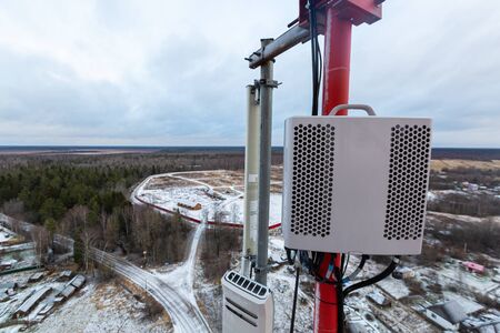 Red telecommunication tower or mast with vertical panel antenna, remote electric tilt and remote...