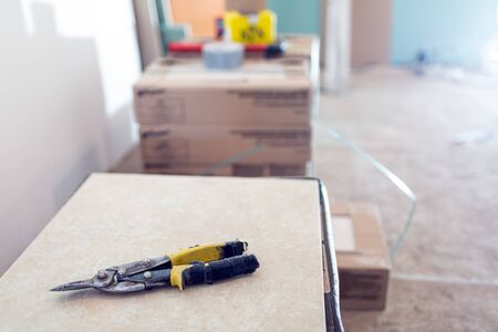 Construction knife is on the tile in room of the apartment with construction materials that is under construction, remodeling, renovation, overhaul, extension, restoration and reconstruction. Concept of home improvement.の写真素材
