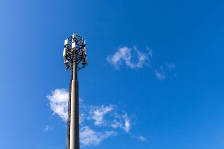 Telecommunication tower with microwave equipment, radio panel antennas, outdoor remote radio units, power cables, coaxial cables, optic fibers, climatic vandal-proof cabinets are installed on the mast.の写真素材
