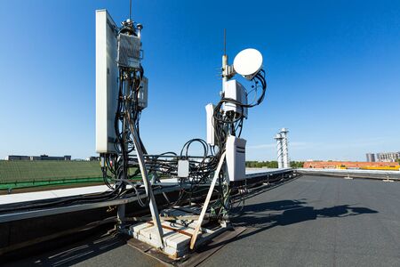 Metal constructions for telecommunication data equipment, radio panel antennas, outdoor remote radio units, power cables, coaxial cables, optic fibers on the roof. Outside part of telecommunication basic station.の写真素材