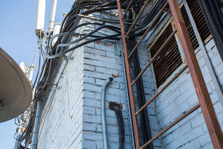 Russia, Saint-Petersburg - April 30, 2018: Cables are near of climatic vandal-proof cabinet with microwave equipment and power cables, coaxial cables, optic fibers. Typical basic station of telecommunication operators.のeditorial素材