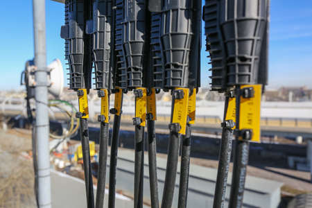 Russia, Saint-Petersburg - April 30, 2018: Protective covers of optic cables connected to telecommunication radio panel antenna from outdoor remote radio units of Base Transceiver Station (BTS) are installed on roof of a building. Outside part 5G, 4G, 3G,のeditorial素材
