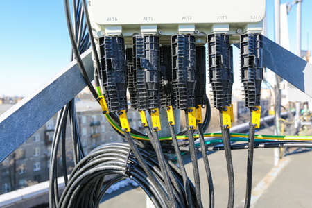 Russia, Saint-Petersburg - April 30, 2018: Protective covers of optic cables connected to telecommunication radio panel antenna from outdoor remote radio units of Base Transceiver Station (BTS) are installed on roof of a building. Outside part 5G, 4G, 3G,のeditorial素材