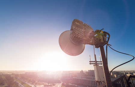 Radio antennas with outdoor radio unit and power cables, coaxial cables, optic fibers on the metal construction for telecommunication data equipment or mast in city. Outside part of telecommunication basic stationの写真素材