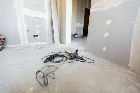 Working process of installing plasterboard or drywall - for making gypsum walls in apartment is under construction, remodeling, renovation, extension, restoration and reconstruction and manual tools - concrete mixer and perforator are on the floorの写真素材