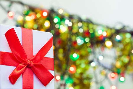 Box with christmas gift with red bow and christmas bokeh light abstract holiday backgroundの写真素材