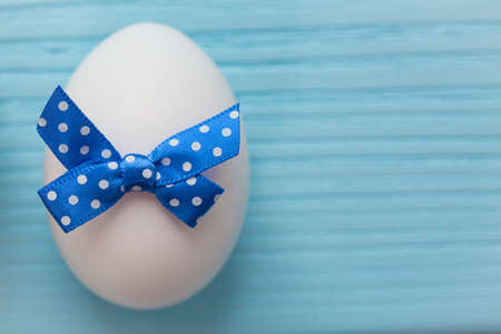 Blue colored Easter egg with white spotted is on the wooden background.の写真素材