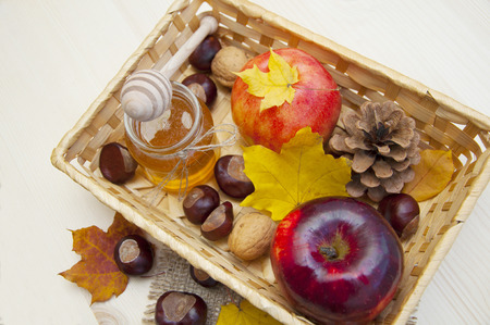 Glass jar of honey with apples, chestnuts and walnuts on a wooden backgroundの写真素材