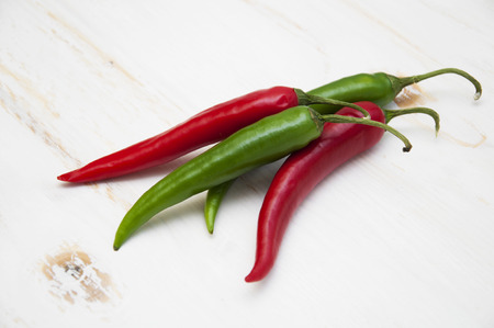 Red and green chili peppers on the white wooden backgroundの写真素材