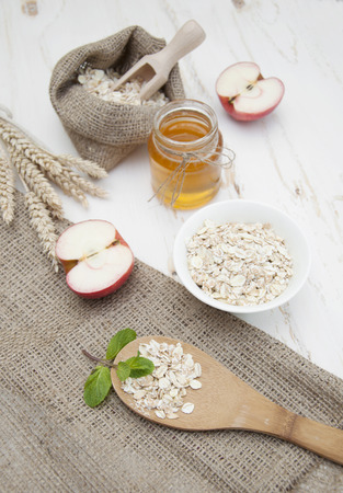 Oat flakes on a white bowl,apples and honey on a white wooden backgroundの写真素材