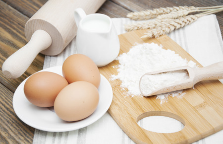 Bread Ingredients - flour, eggs,wheat and milk on a wooden backgroundの写真素材