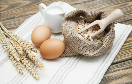 Bowl of oats with eggs and milk on a dark wooden backgroundの写真素材