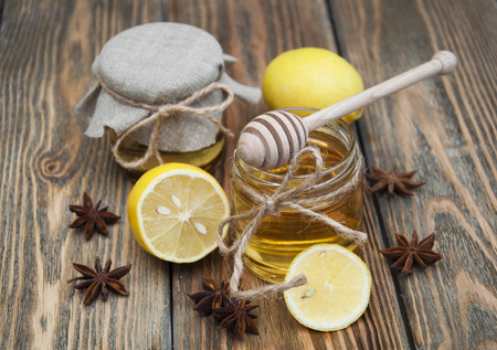 Fresh glass pot of sweet honey with spices and lemon on wooden backgroundの写真素材
