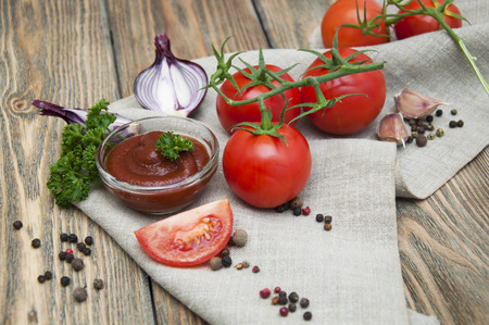 Tomatoes and tomato sauce with spices on a wooden backgroundの写真素材