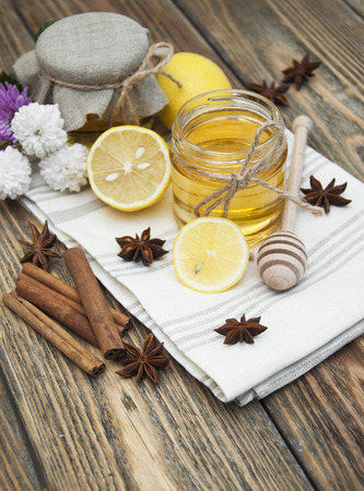 Fresh glass pot of sweet honey with spices and lemon on wooden backgroundの写真素材