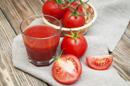 Fresh tomatoes and a glass full of tomato juice on a napkinの写真素材