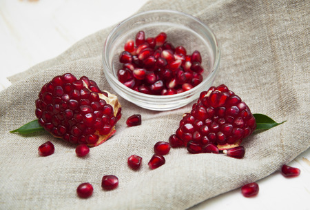 Juicy pomegranate and red grains on wooden backgroundの写真素材