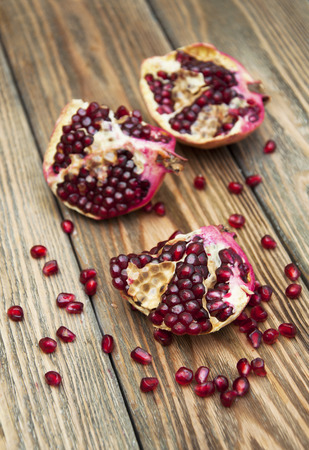Piece of ripe pomegranate and red grains on wooden tableの写真素材