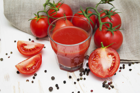 Fresh tomatoes and a glass full of tomato juice on a wooden backgroundの写真素材