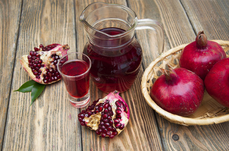 Pomegranate juice in a glass and jug on a wooden backgroundの写真素材