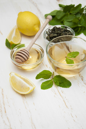 A cup of tea with honey, lemon and mint on a wooden backgroundの写真素材
