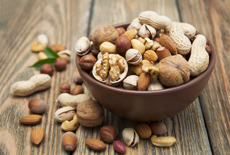 Mixed nuts in a bowl on a wooden backgroundの写真素材