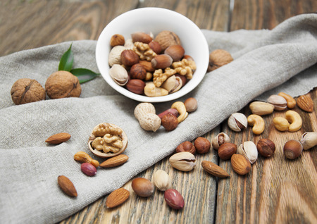 Mixed nuts in a bowl on a wooden backgroundの写真素材