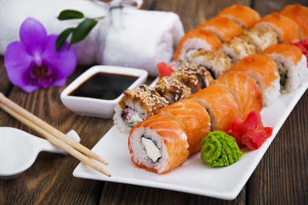 Different Sushi rolls,wasabi and ginger on a plate on wooden backgroundの写真素材