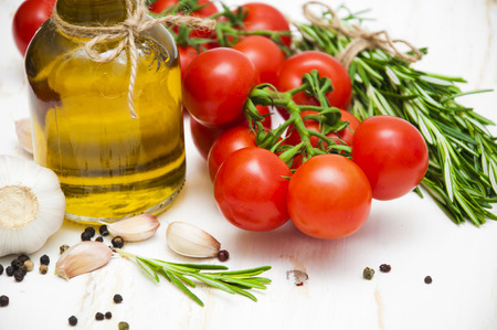 Olive oil, cherry tomatoes, garlic and rosemary on a white wooden backgroundの写真素材