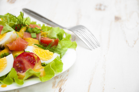 Mixed salad with slices of salmon and honey mustard sauce on a wooden backgroundの写真素材