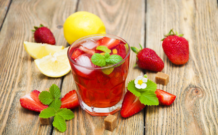 Cold strawberry drink with fresh strawberries and lemon on wooden backgroundの写真素材