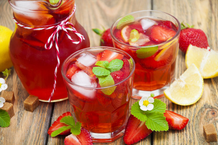 Cold strawberry drink with fresh strawberries and lemon on wooden backgroundの写真素材