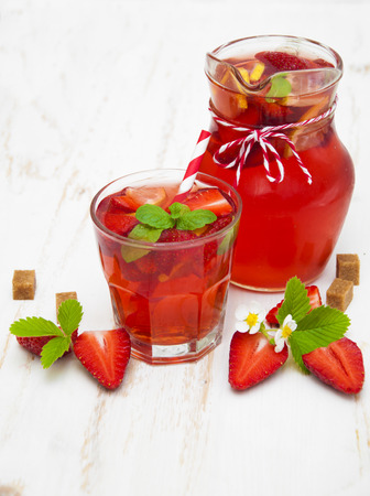 Cold strawberry drink with fresh strawberries and lemon on white wooden backgroundの写真素材