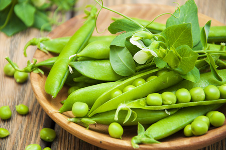Organic green peas in a plate on a wooden backgroundの写真素材