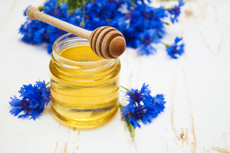 Fresh honey with cornflowers flowers on wooden white backgroundの写真素材