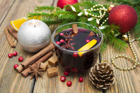 Glass of mulled wine with spices and Christmas decoration on a wooden backgroundの写真素材