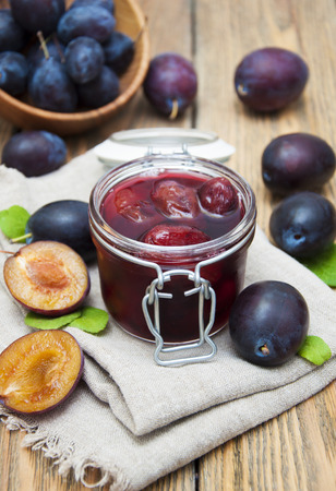Plum jam in a glass jar with fresh plums on wooden backgroundの写真素材