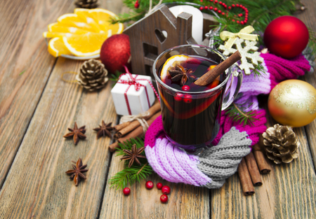 Glass of mulled wine with spices and Christmas decoration on a wooden backgroundの写真素材
