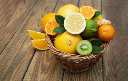 Fresh juicy citrus fruits in a basket on a wooden backgroundの写真素材