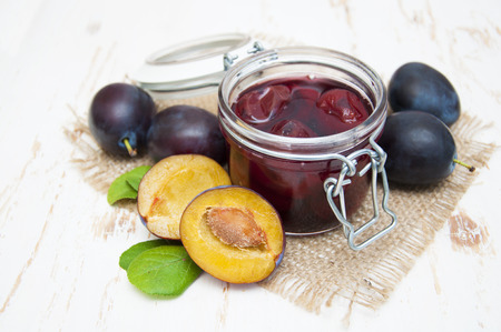 Plum jam in a glass jar with fresh plums on wooden backgroundの写真素材