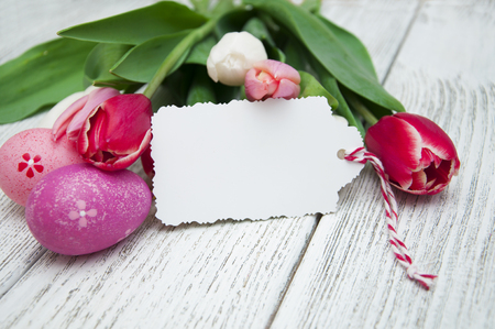 Easter gift card with tulips and Easter eggs on a wooden backgroundの写真素材