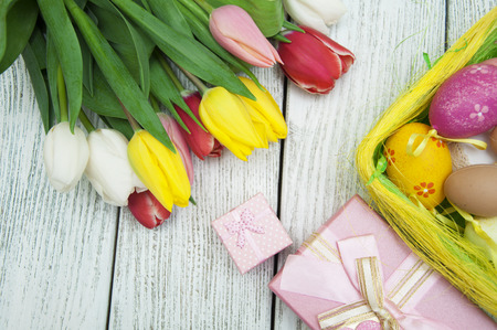 Easter background with colorful eggs and tulips over white wood. Top view with copy spaceの写真素材